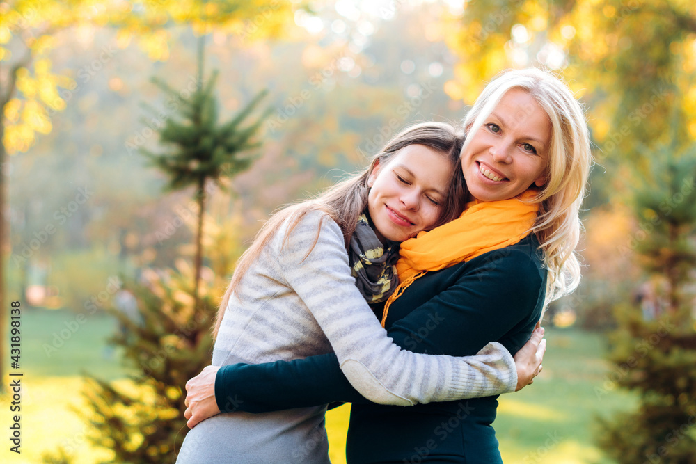 Fototapeta premium Portrait of a mother and daughter in nature, they are hugging, the girl put her head on her mother's shoulder and closed her eyes for joy, a happy joint moment