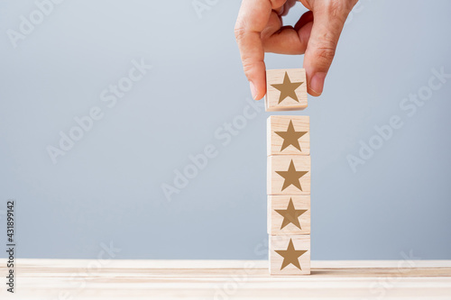 Hand holding wooden blocks with the star symbol. Customer reviews  feedback  rating  ranking and service concept.