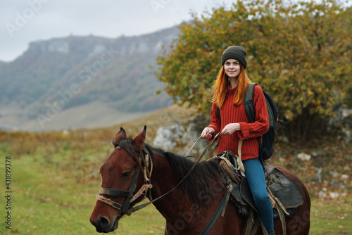 woman hiker with a backpack rides a horse in the mountains nature travel