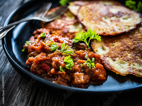 Potato pancakes with vegetable stew on wooden table 
