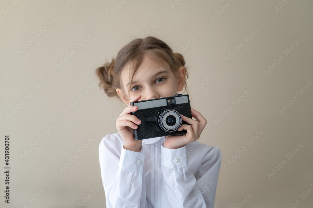 Portrait of a beautiful caucasian little girl with fashionable hairstyle, wearing jeans and a white shirt holding vintage camera Portrait of a beautiful caucasian little girl with fashionable hairstyle, wearing jeans and a white shirt holding vintage camera