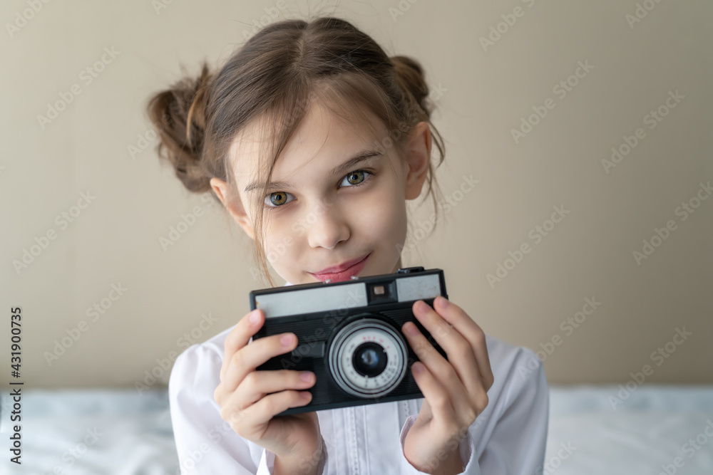 Portrait of a beautiful caucasian little girl with fashionable hairstyle, wearing jeans and a white shirt holding vintage camera Portrait of a beautiful caucasian little girl with fashionable hairstyle, wearing jeans and a white shirt holding vintage camera