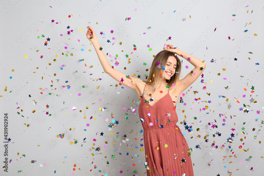 Happy woman and falling confetti on light grey background Happy woman and falling confetti on light grey background