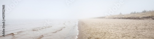 Sandy shore of the Baltic sea in a thick white morning fog. Early spring in Latvia. Idyllic rural scene. Nordic walking, recreation, eco tourism, environmental conservation concepts