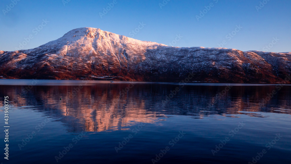 Naklejka premium Snowy mountain in Norwegian sunset.