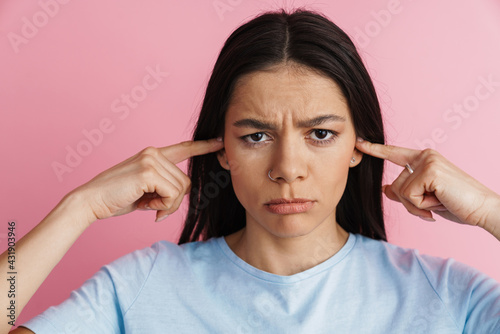 Young displeased woman plugging her ears and frowning