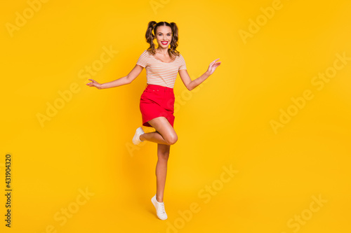 Photo of funny lady stand tiptoe wear striped shirt short skirt sneakers isolated yellow color background