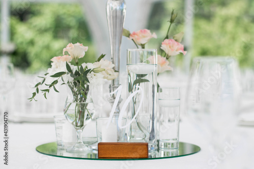 Close-up of a wedding dinner table at reception. Fresh flowers and candles on mirros plate. Wedding decorations. photo