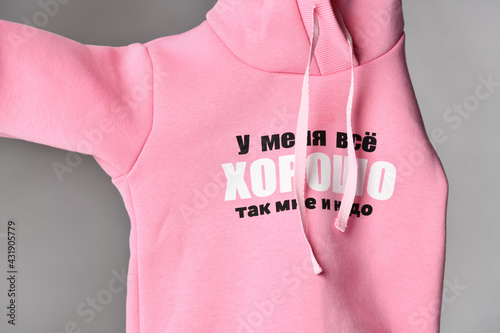 Close-up on the text of the inscription on the pink jersey overalls, sweater, sweatshirt, t-shirt, fabric, fabric. Translation: I'm fine, that's what I need