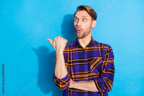 Photo of impressed positive person look interested indicate thumb empty space isolated on blue color background