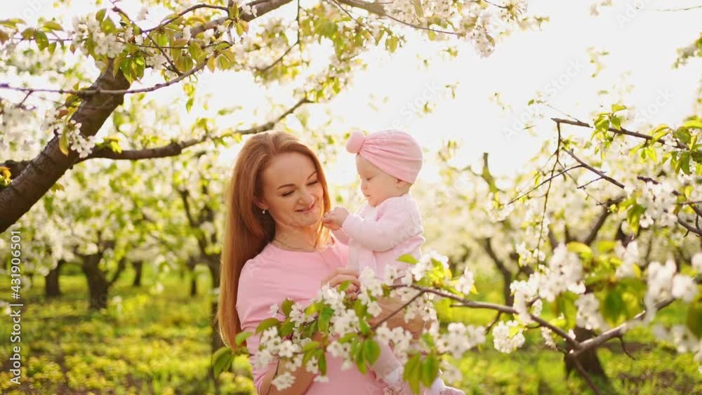 mother with baby in arms in flowering garden. surgery for child with cleft lip.