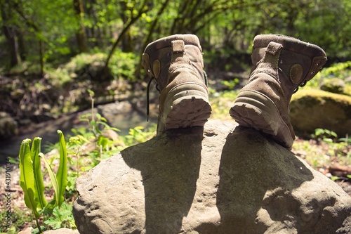An experienced tourist's boots are drying in the sun on a warm spring day on a stone in the forest. Shallow depth of field. A large black beetle climbs the stone. Travel atmosphere.