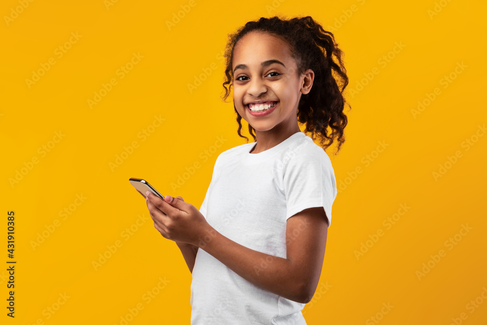 Smiling black girl using mobile phone at studio Smiling black girl using mobile phone at studio