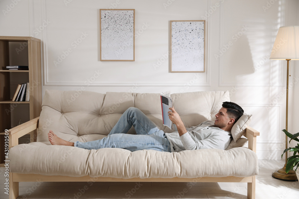 Man reading newspaper on sofa at home Man reading newspaper on sofa at home