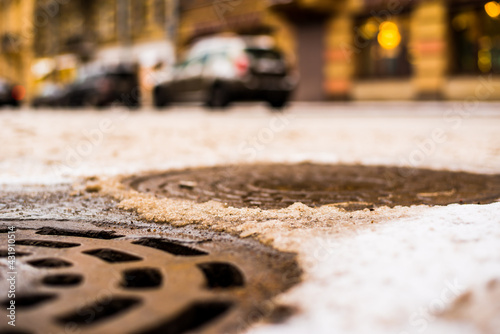 Snowy winter in the big city, the car traveling on the street. Close up view of a hatches at the level of the asphalt