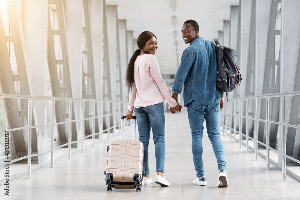Couple Travelling Concept. Romantic Black Spouses Walking With Luggage In Airport