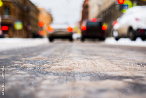 Snowy winter in the big city, the cars stopped at red traffic light signal. Close up view from the asphalt level