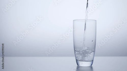 Clean drinking water pours into the glass. A light background with a copy of the space.