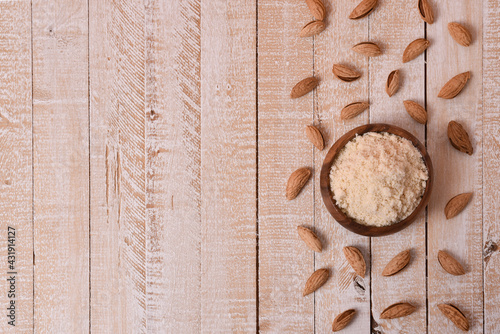 almond flour in a wooden bowl on a white wooden table with nuts with copy space