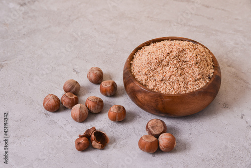 hazelnut flour in a wooden bowl on a stone table with nuts