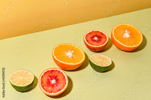 citrus fruits cut in half in a row on a yellow-green background with copyspace
