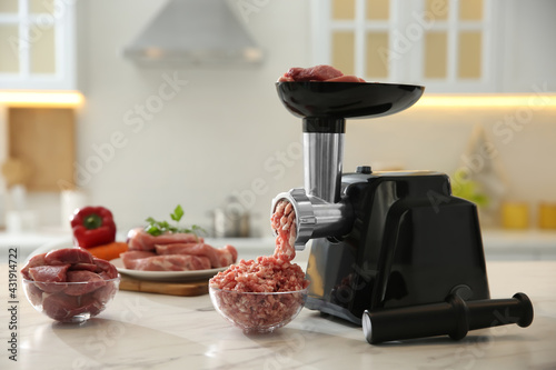 Φωτογραφία Modern meat grinder and products on white marble table in kitchen