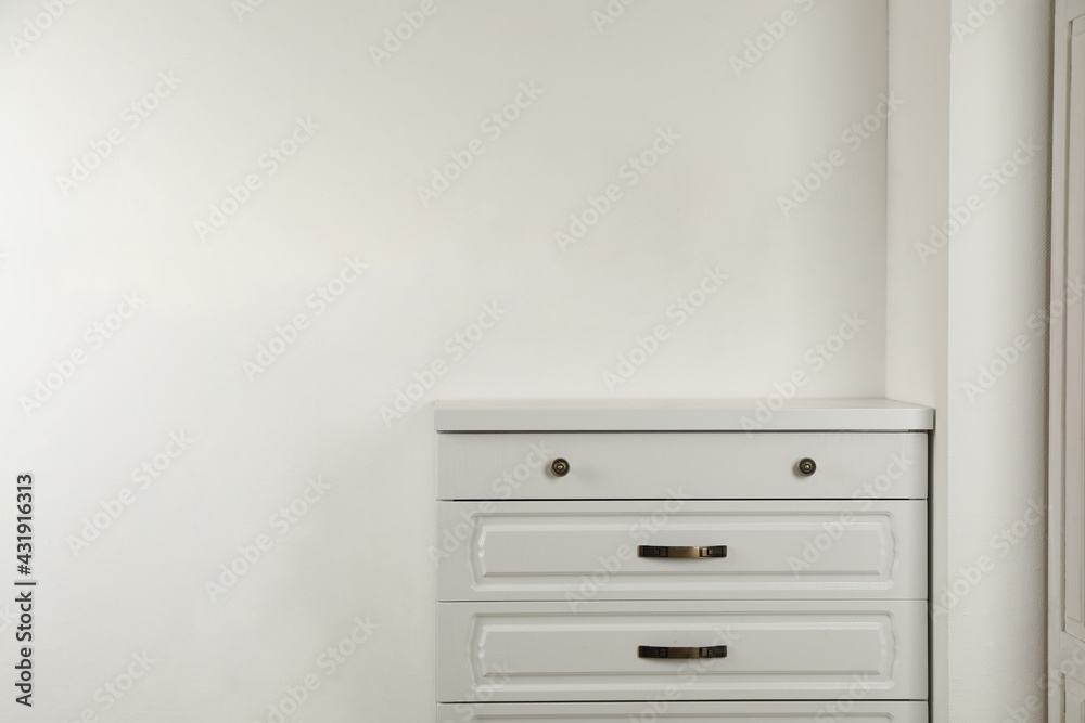 Modern chest of drawers near white wall Modern chest of drawers near white wall