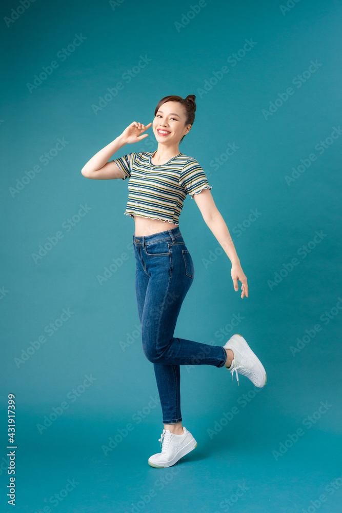 Full length portrait of a cheerful casual asian woman jumping isolated over blue background Full length portrait of a cheerful casual asian woman jumping isolated over blue background