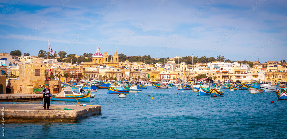 a group of people sitting in a harbor next to a body of water in Malta