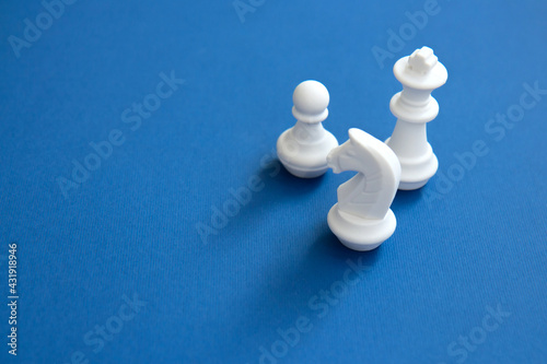 Chess pieces on a bright blue background. Abstract background. White chess figures for the game and strategy. Colorful chess concept