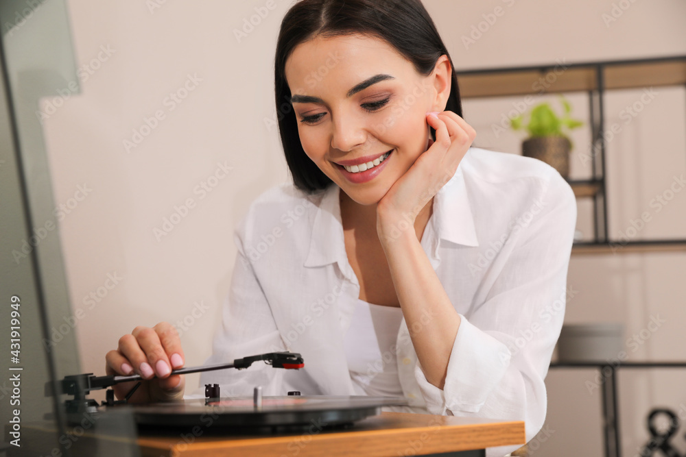 Happy young woman using turntable at home