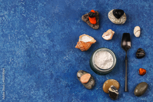 Healthy lifestyle concept. Hydrolyzed marine collagen powder in a glass jar among stones on a blue background. Natural supplement. Copy space.