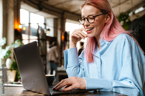 Young beautiful woman smiling and using laptop in cafe