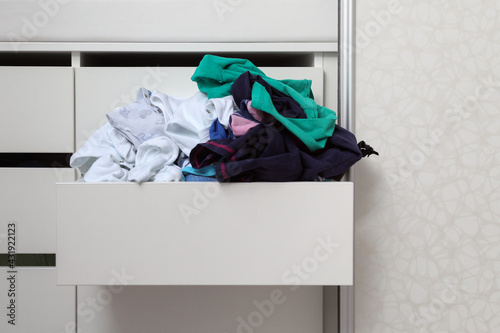 фотографія overflowing sloppy pile of clothes in an open drawer