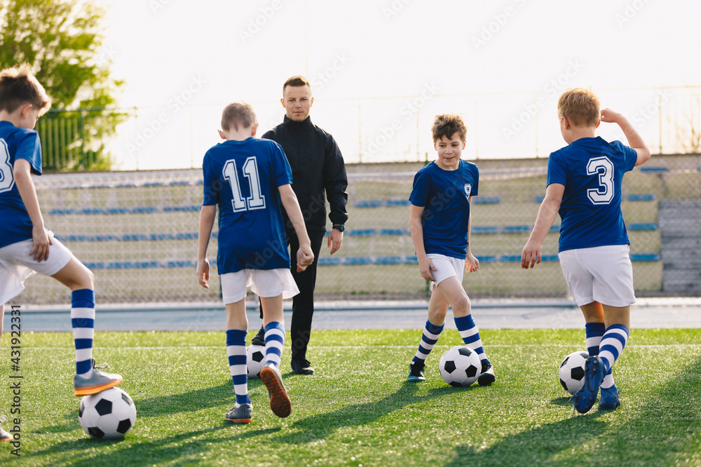 School Boys with Young Sports Coach on Training. Kids Practicing Soccer on Summer Sunny Day. School Boys with Young Sports Coach on Training. Kids Practicing Soccer on Summer Sunny Day.