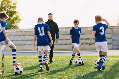 School Boys with Young Sports Coach on Training. Kids Practicing Soccer on Summer Sunny Day. © matimix