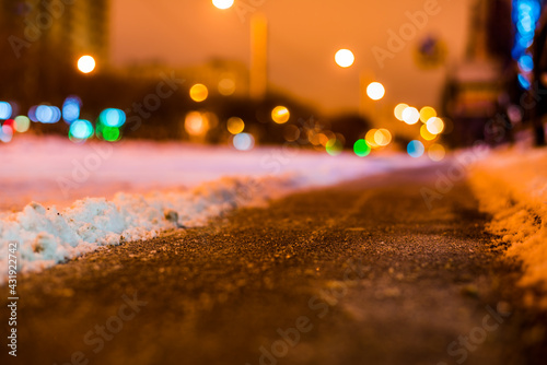 Winter night in the big city, the snow-covered street with a cleared path. Close up view from the asphalt level