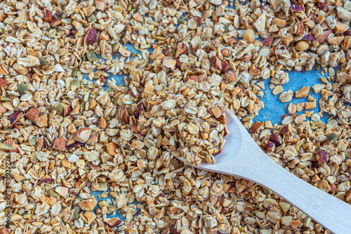 Freshly baked granola, muesli from oat flakes, varius of nuts, honey, pumpkin seeds on baking sheet. Home cooking healthy vegetarian snack. Homemade food concept. Keto diet. photo