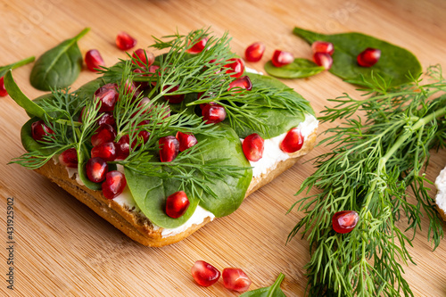 sandwich with fresh cream, spinach leaves, ripe pomegranate grains and green dill