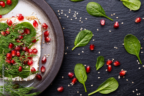 healthy sandwich on a plate - ripe pomegranate grains, young spinach leaves, fragrant dill and fresh cream