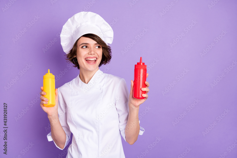 Portrait of lovely cheerful chef holding ketchup bottles national domestic gourmet copy space isolated over bright violet purple color background Portrait of lovely cheerful chef holding ketchup bottles national domestic gourmet copy space isolated over bright violet purple color background