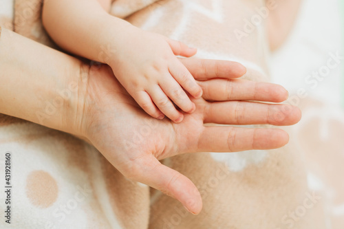 Small hand of a newborn baby in the hand of an adult.