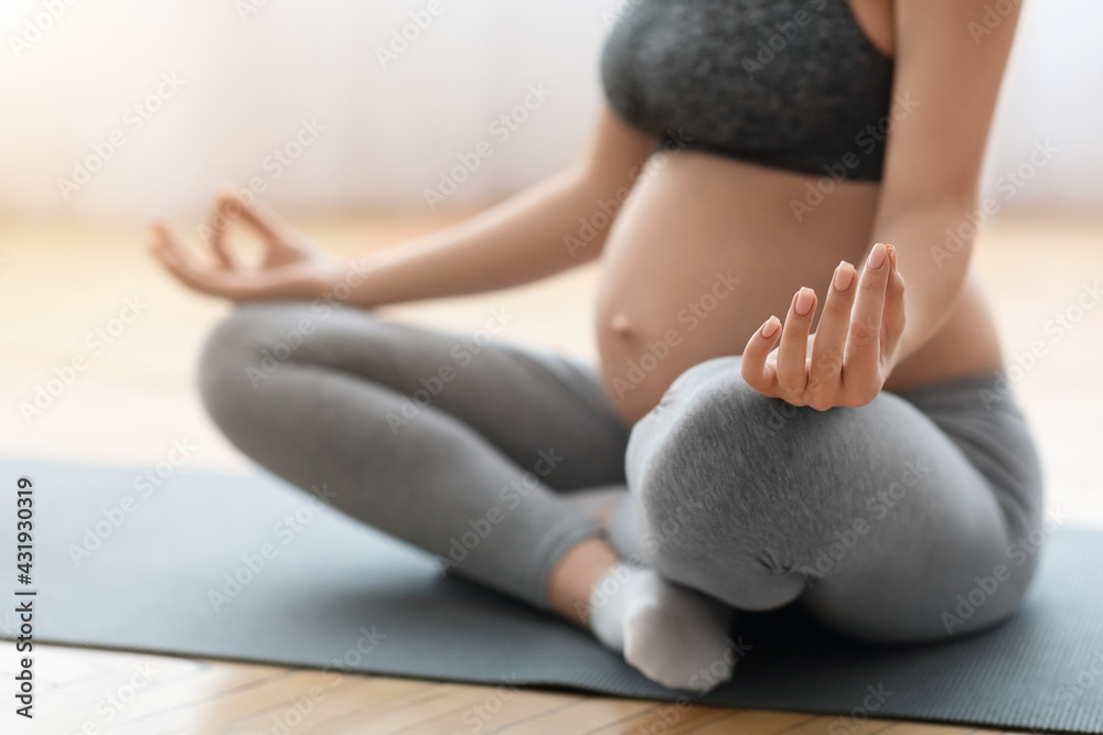 Fototapeta premium Closeup Shot Of Unrecognizable Pregnant Woman Sitting In Lotus Pose