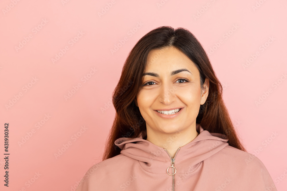 Young woman's portrait on pink studio background. Concept of human emotions, facial expression, youth, sales, ad.