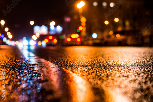 Rainy night in the big city, the passing cars on the road. Close up view from the level of the dividing line