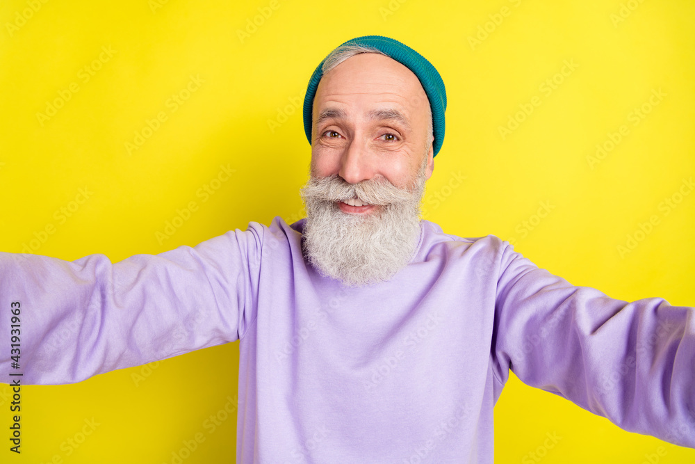 Photo portrait of elder cheerful man taking selfie smiling isolated on bright yellow color background