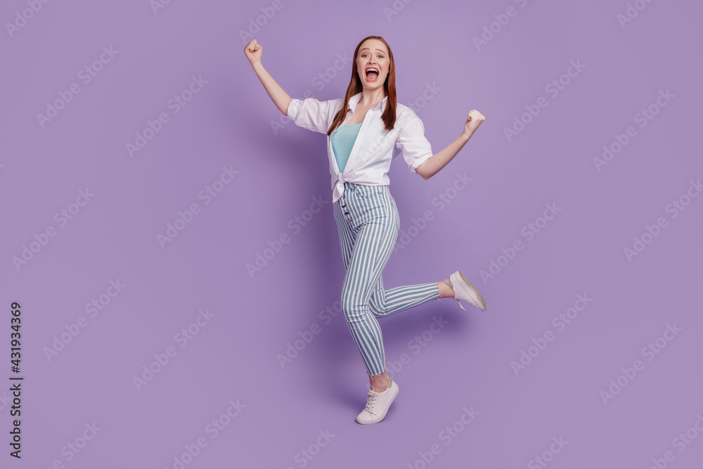 Portrait of cheerful astonished lady raise fists scream on purple background