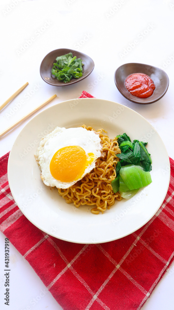 instant noodles served with egg fried and mustard greens on plate. instant fried noodle indomie
