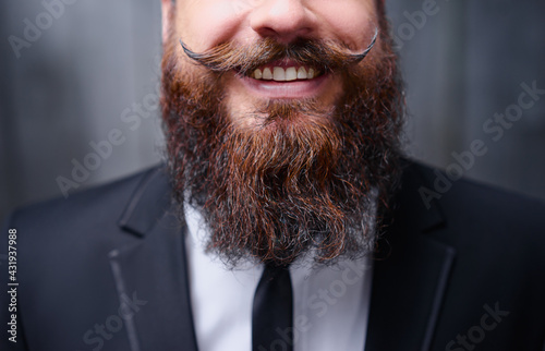 Funny beard and mustache. Close-up of young bearded man showing tongue. photo