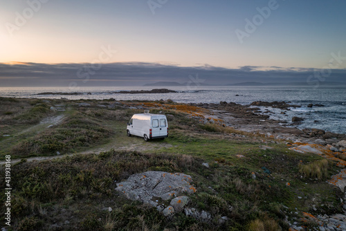 Camper van motorhome with solar panels drone aerial view on a sea landscape with mountains living van life in Galiza, Spain photo